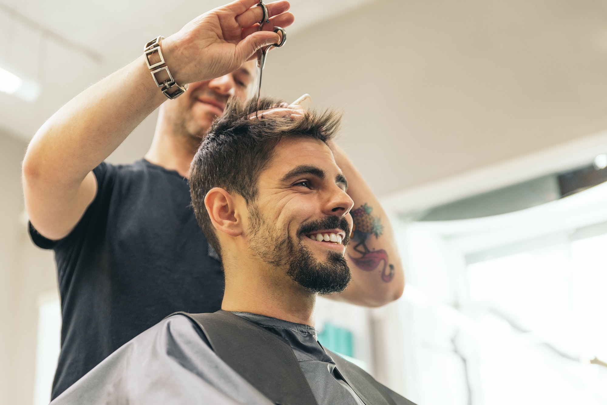Hairstylist making men's haircut to an attractive man.