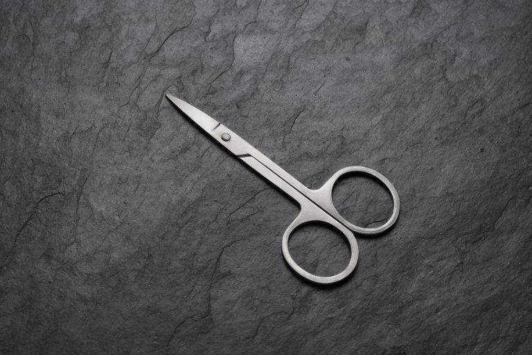 Nail scissors for manicure on black slate background